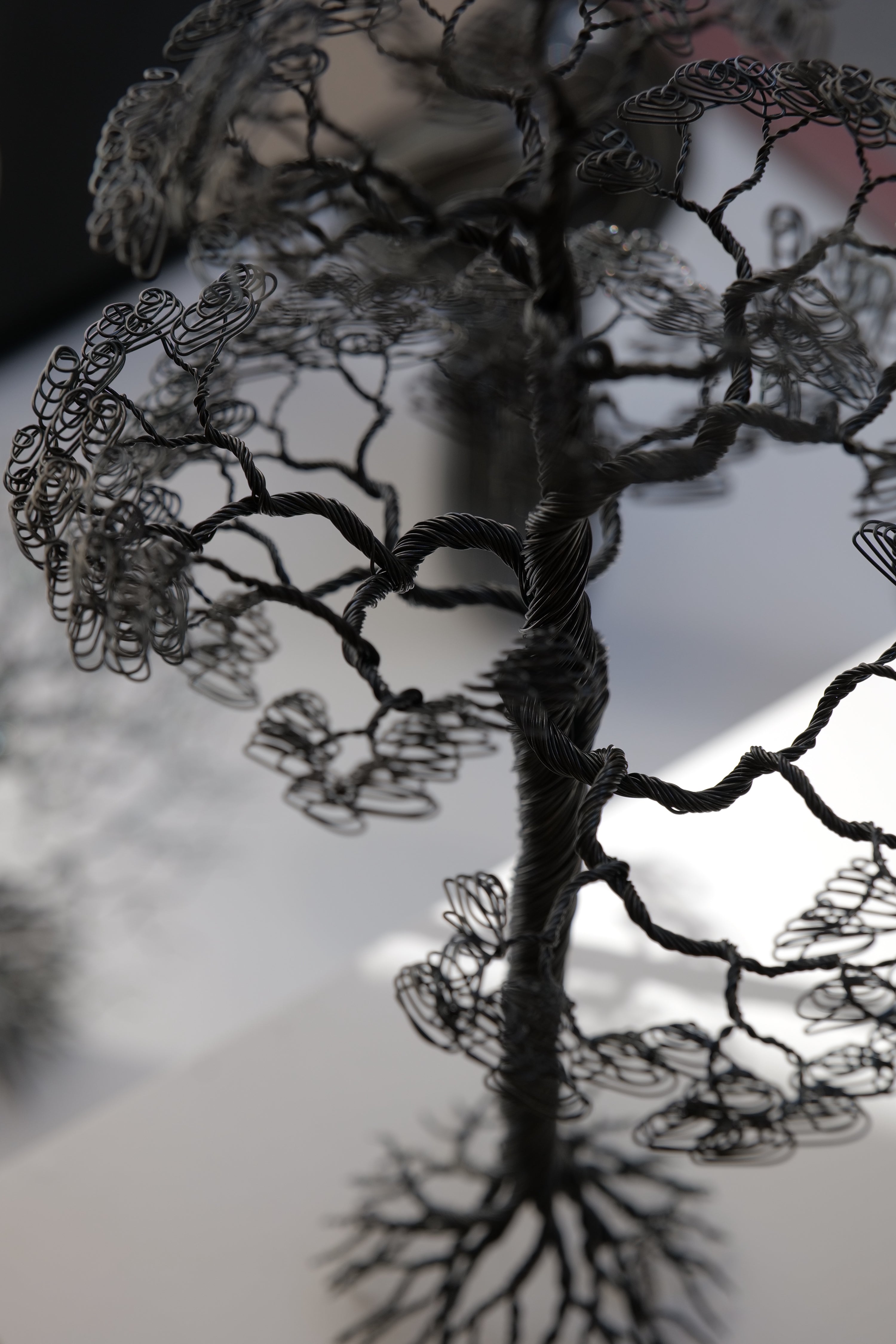 En detaljerad trädskulptur av Matilda Bengtsson, skapad av svart järntråd, som föreställer en ek med realistiska grenar och löv, vilket framhäver naturens skönhet och precision.
