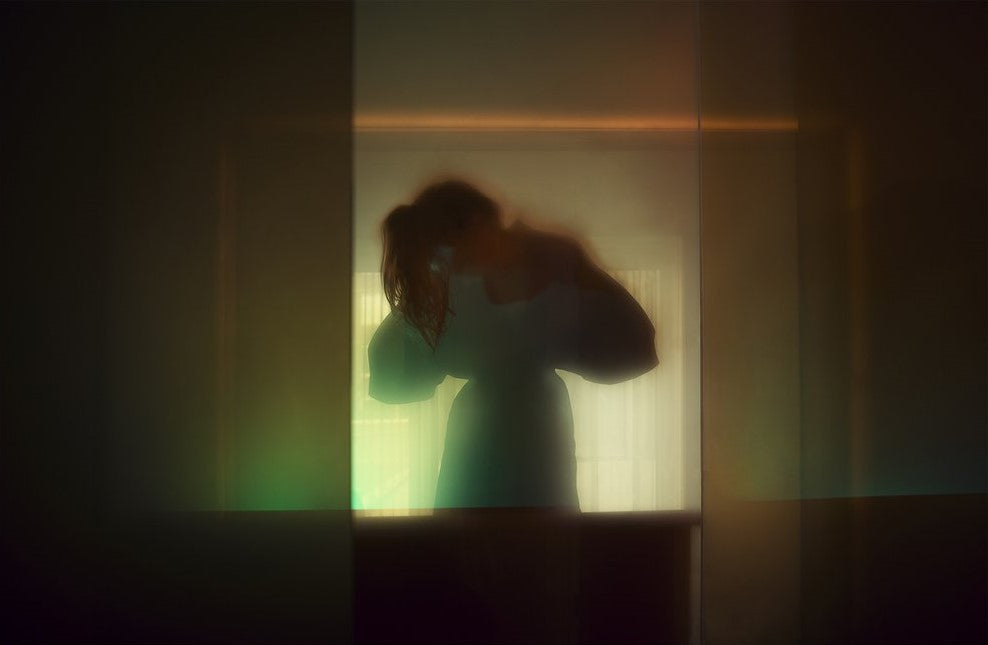 Fotokonst av Andreas Lundberg, med en suddig kvinna i ett rum med dämpad belysning.